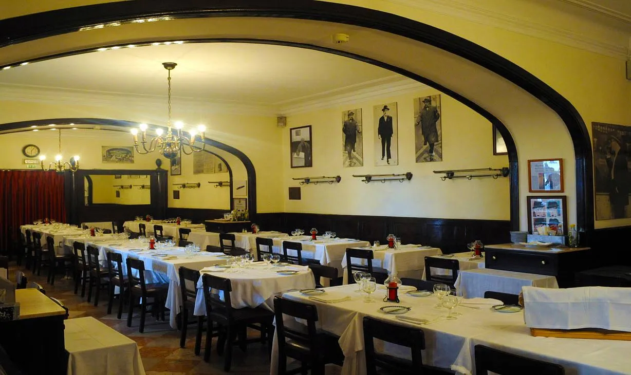 A sala, entre madeira escura e os retratos.